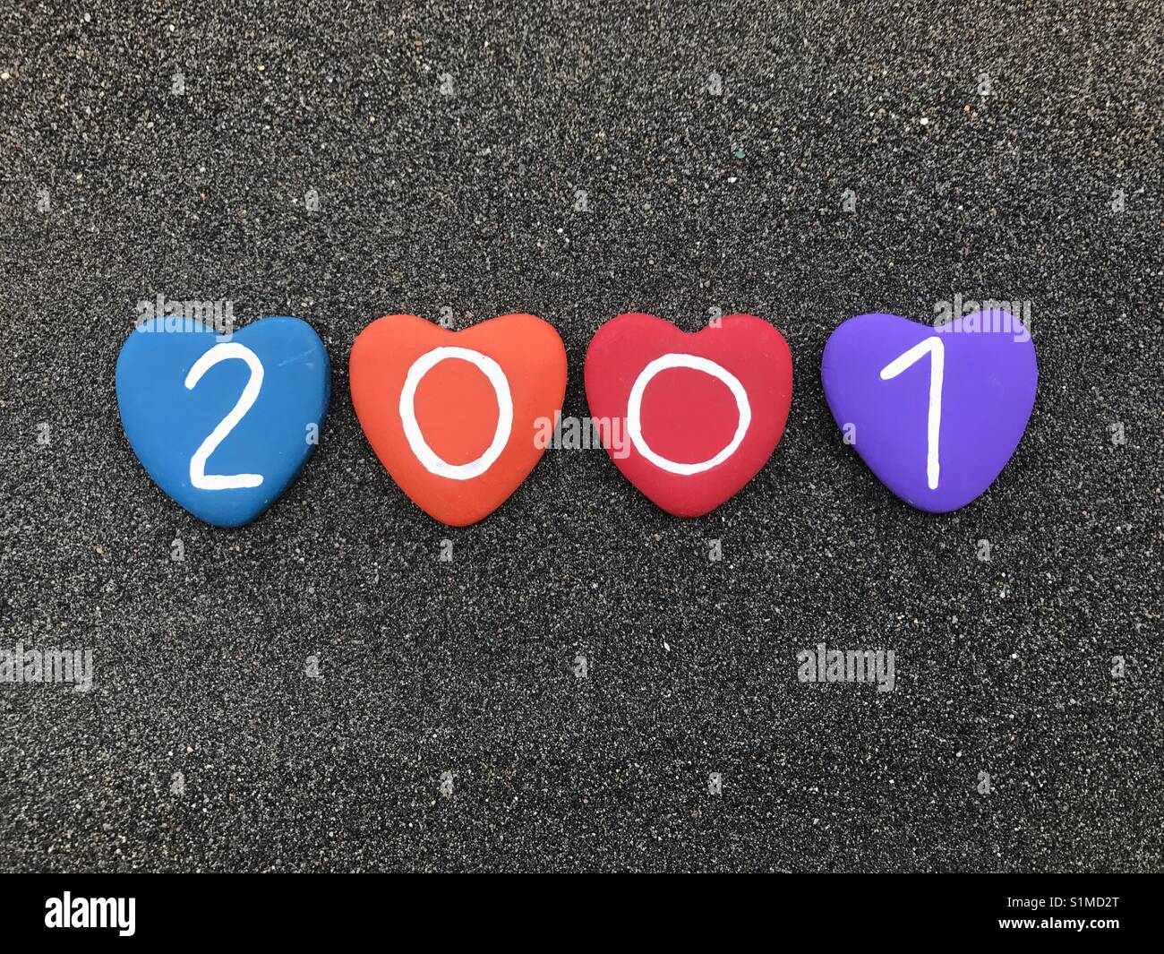 2001 year with colored heart stones over black volcanic sand - Smartphone Captured Stock Image