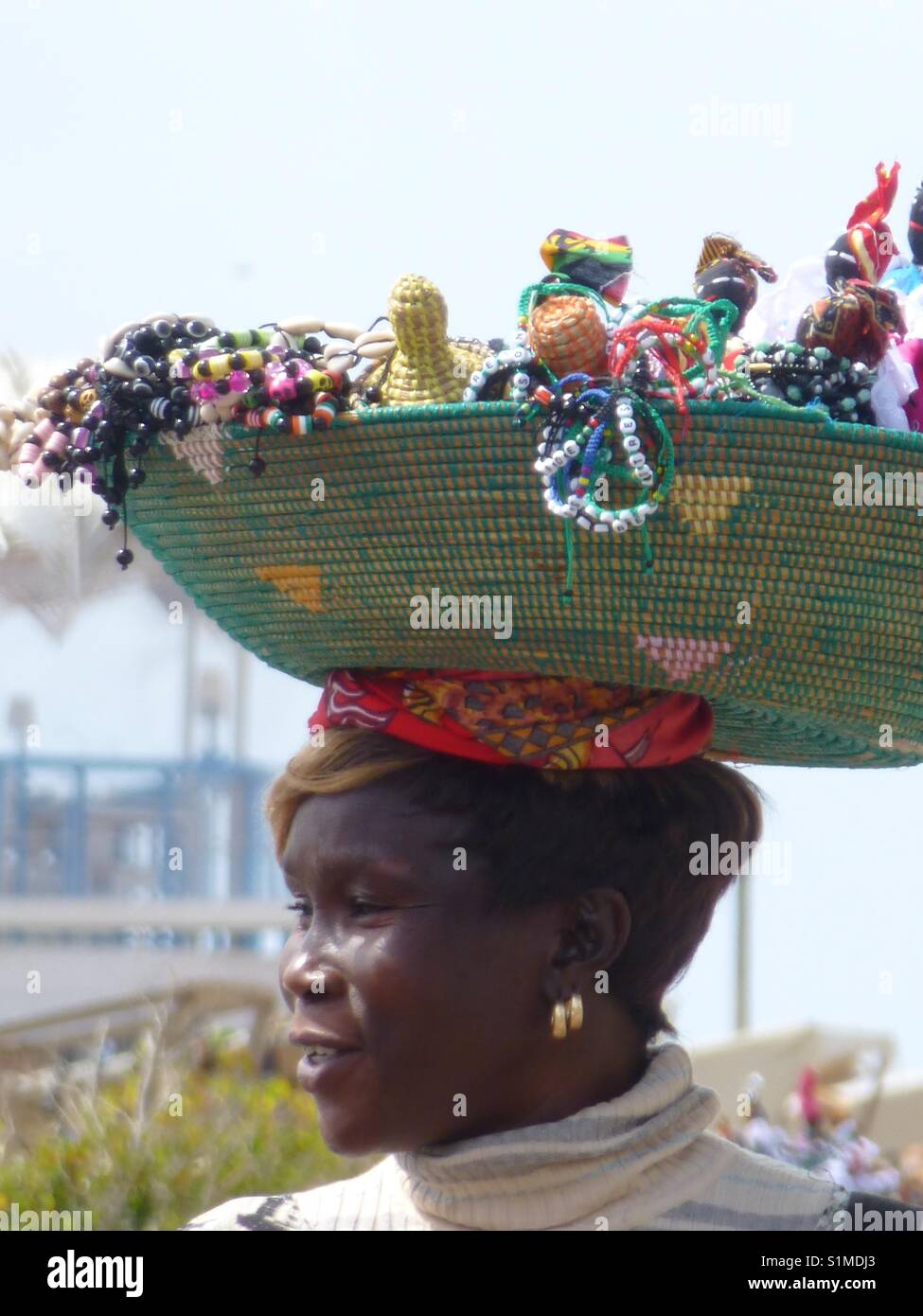 A Beautiful Souvenir Seller Carrying Her For Sale Items On Her Head In Cape Verde...x Stock Photo
