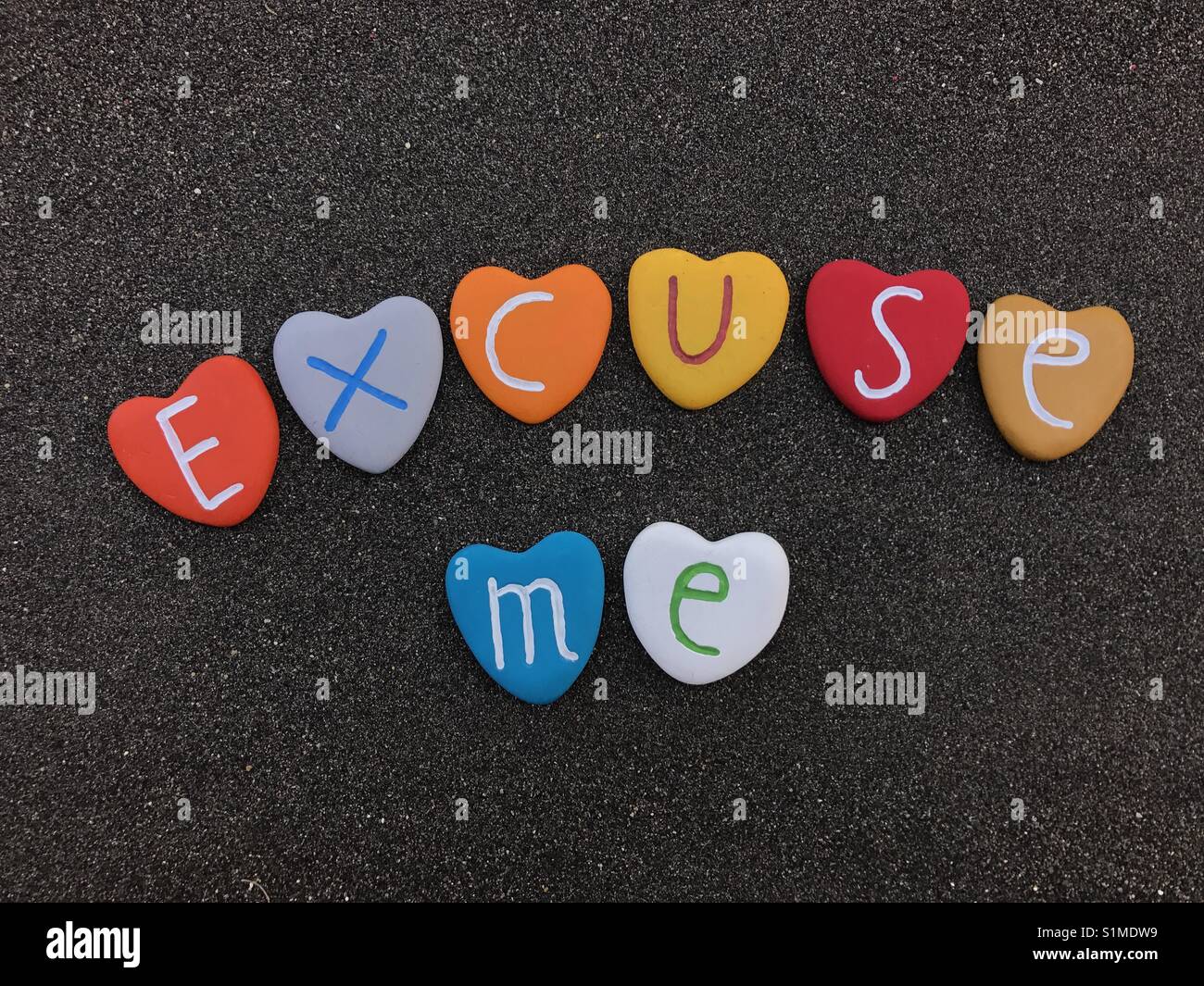 Excuse me with colored heart stones over the black colored stones - Smartphone Captured Stock Image