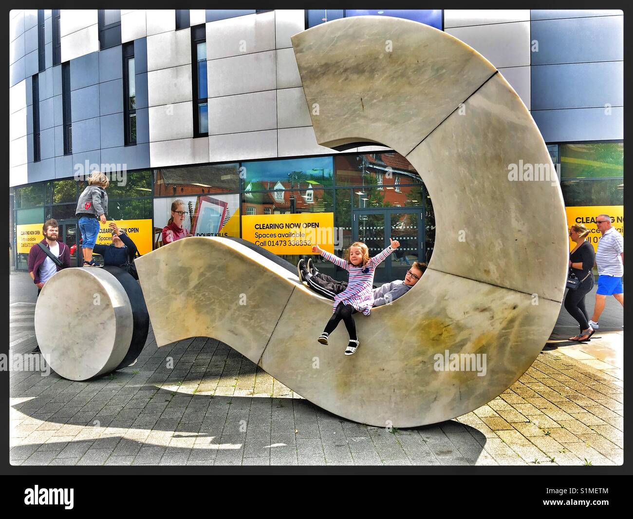 Children playing on a question mark sculpture at the University of