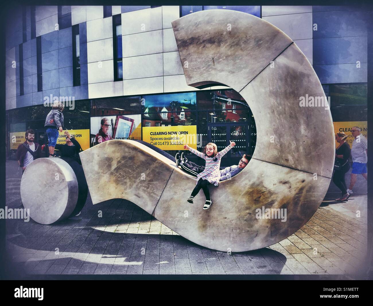 Children playing on the Question Mark sculpture at the University of