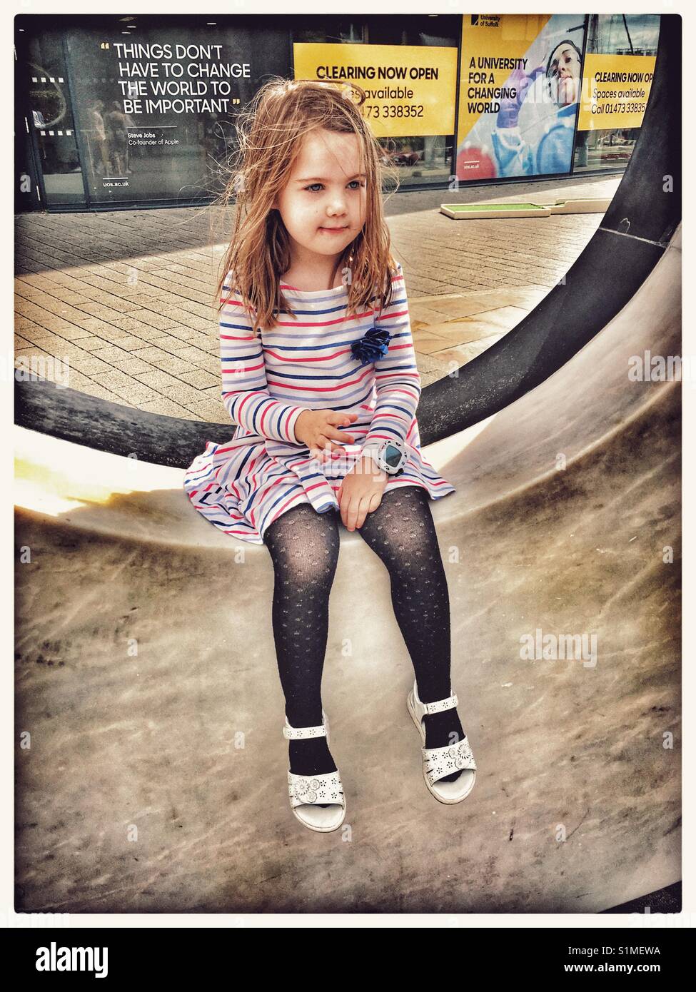 5 year old girl sitting on a sculpture. Stock Photo
