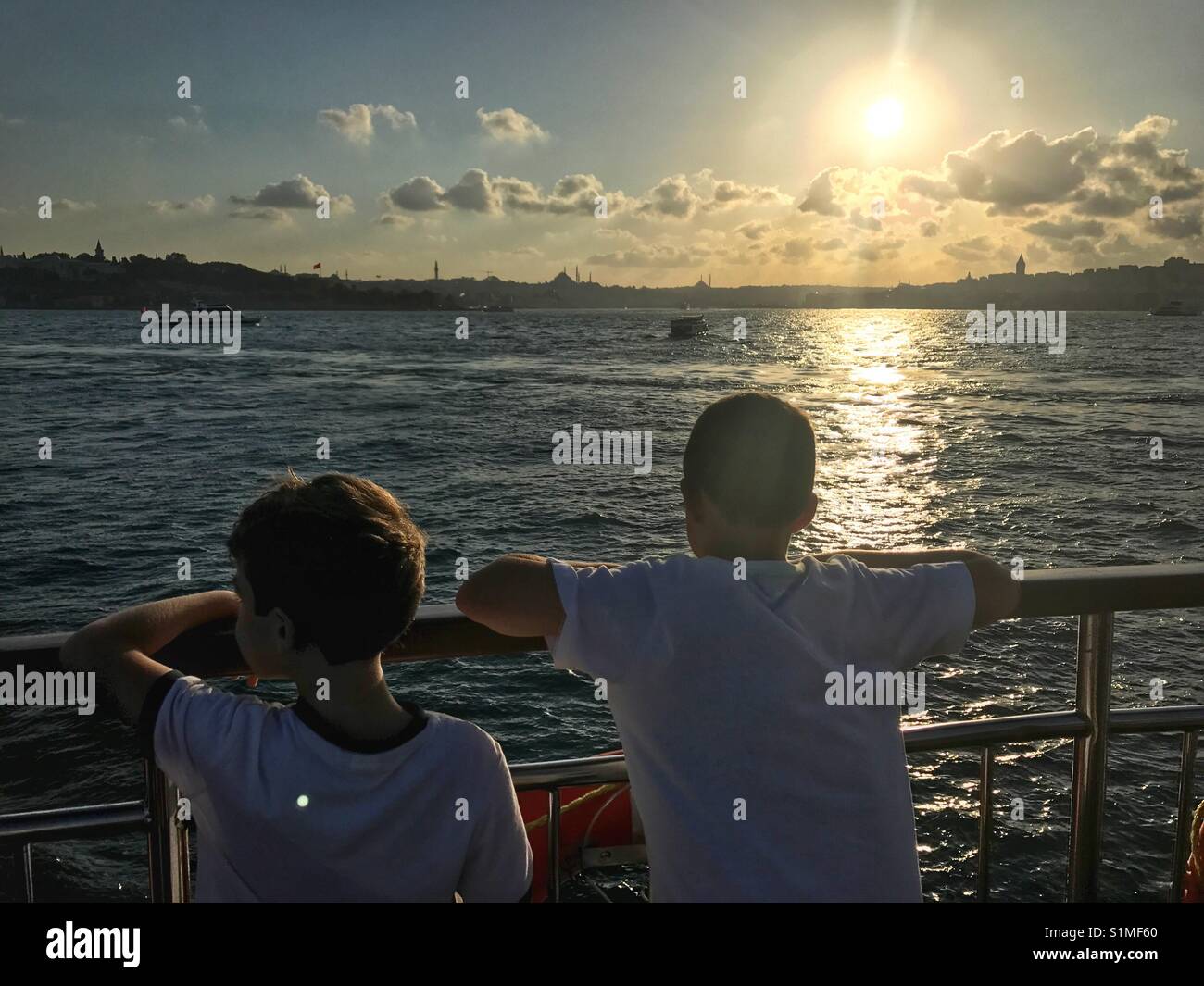 Two tourist kids enjoying the view from the ferry boat trip crossing the Bosporus water - Smartphone Captured Stock Image