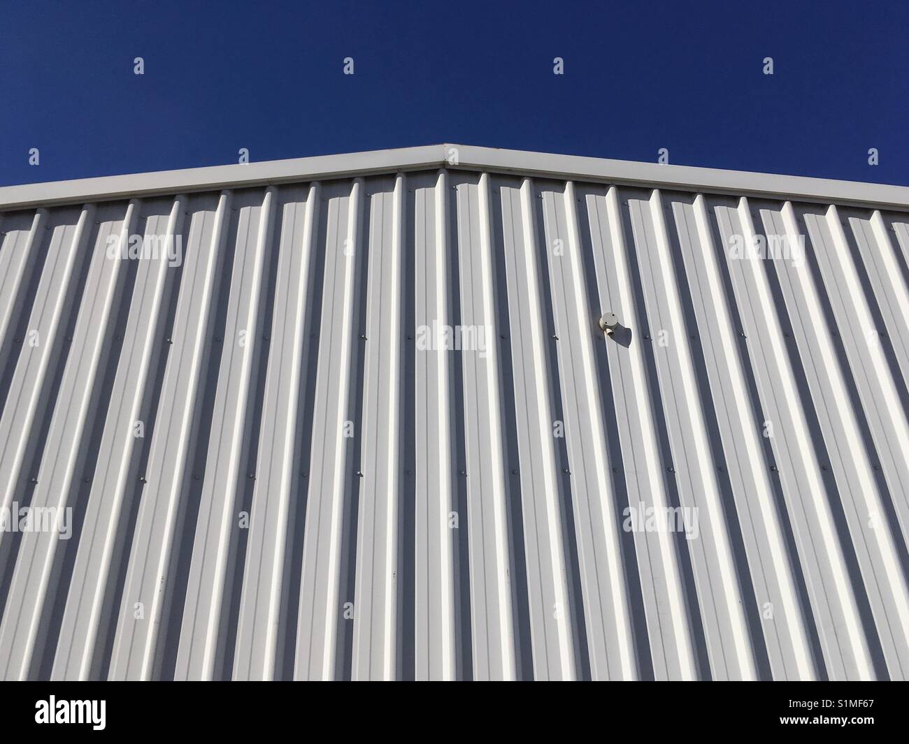 White shed against blue sky. - Smartphone Captured Stock Image