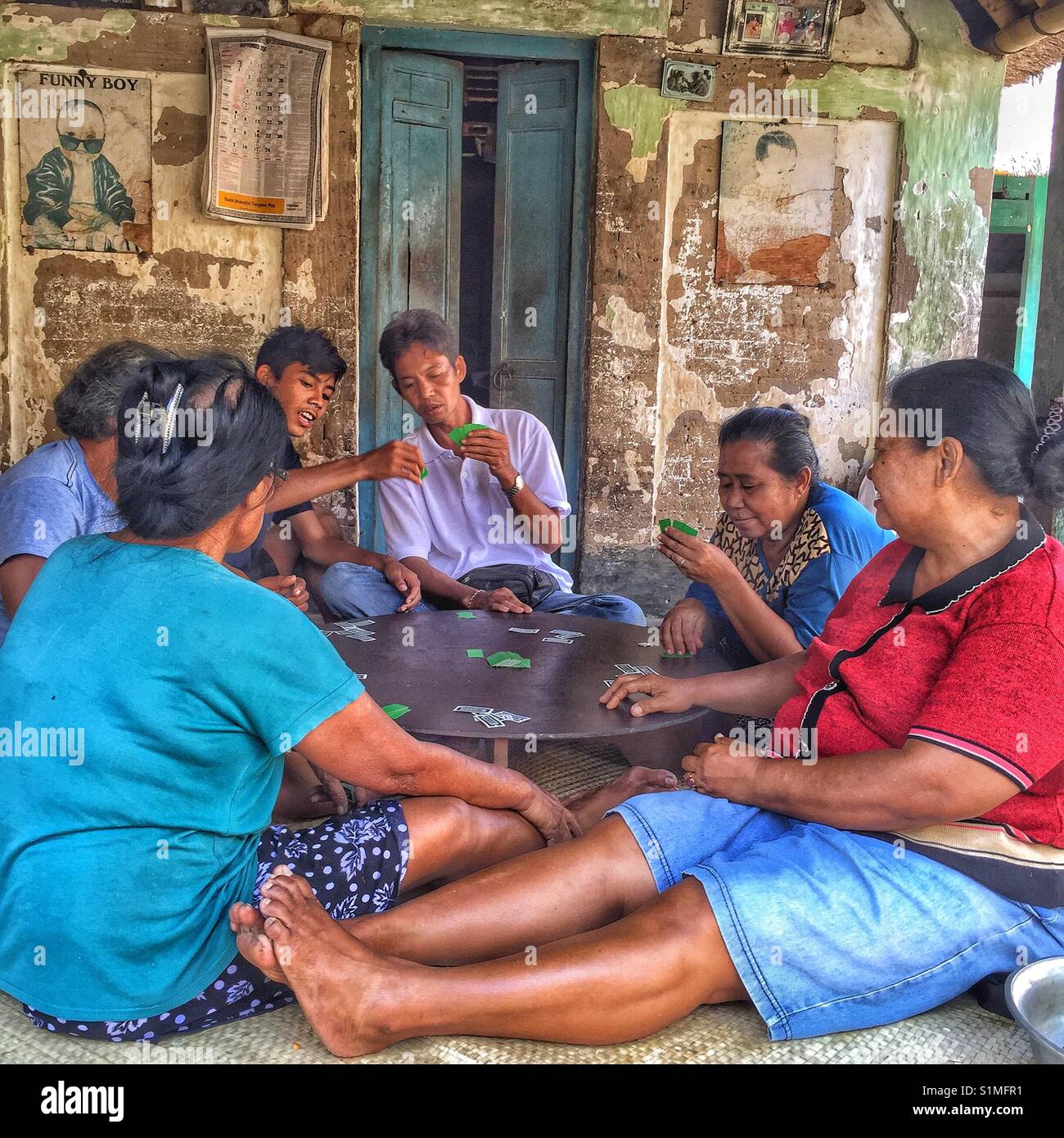 Group of six mature people sitting on ground playing a card game. Bali, Indonesia Stock Photo
