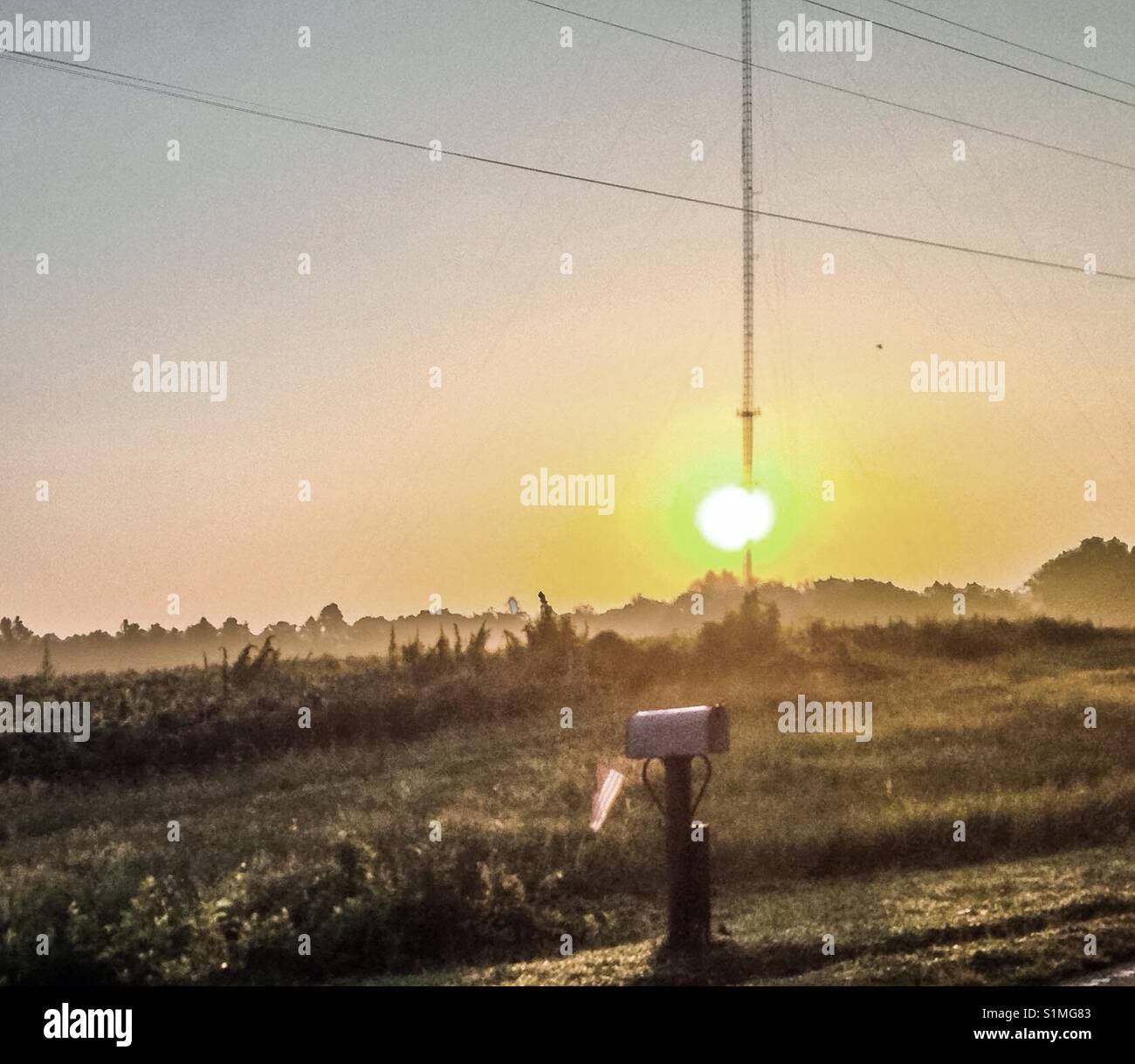 Sunrise directly behind cell tower with mailbox and American flag - Smartphone Captured Stock Image