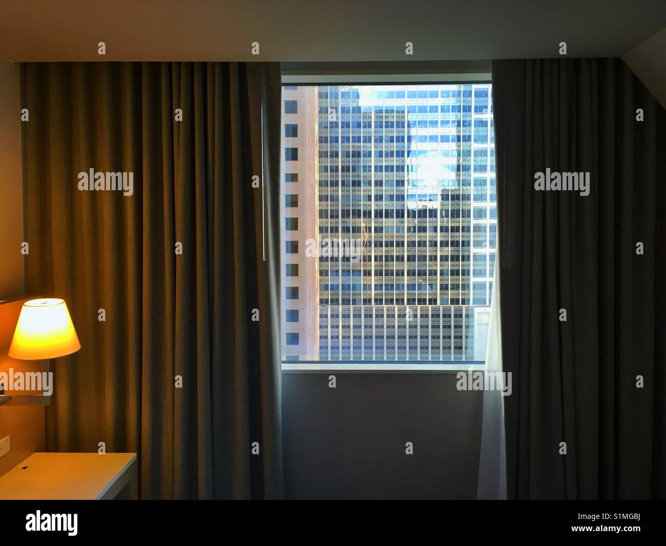 Bedroom with and open curtains and a view at the skyscrapers glass windows - Smartphone Captured Stock Image