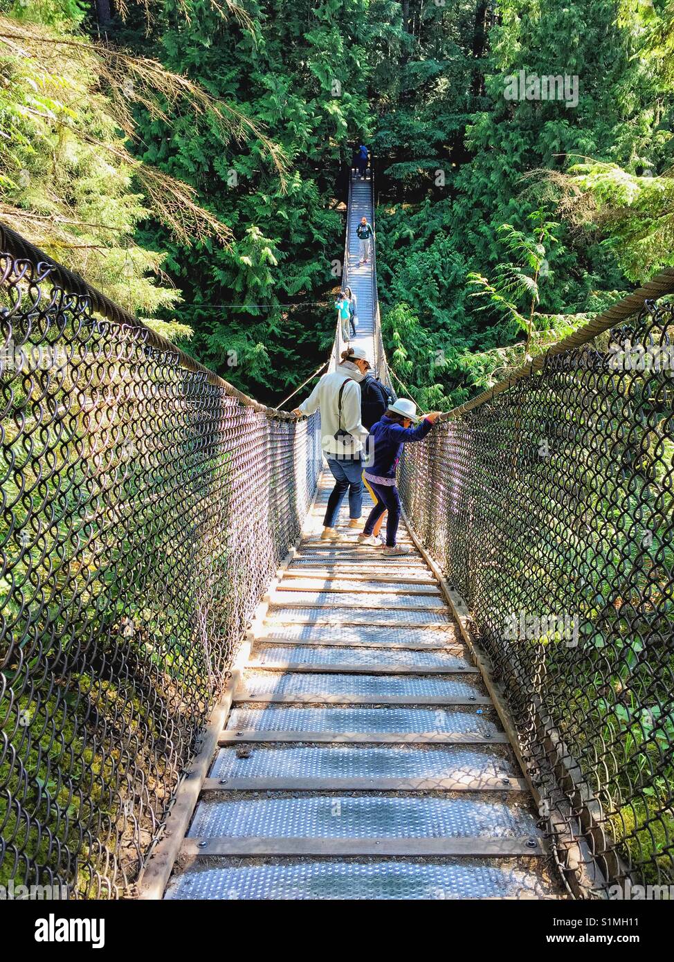 Mother encourages daughter across Lynn Canyon suspension bridge, North Vancouver, British Columbia, Canada Stock Photo