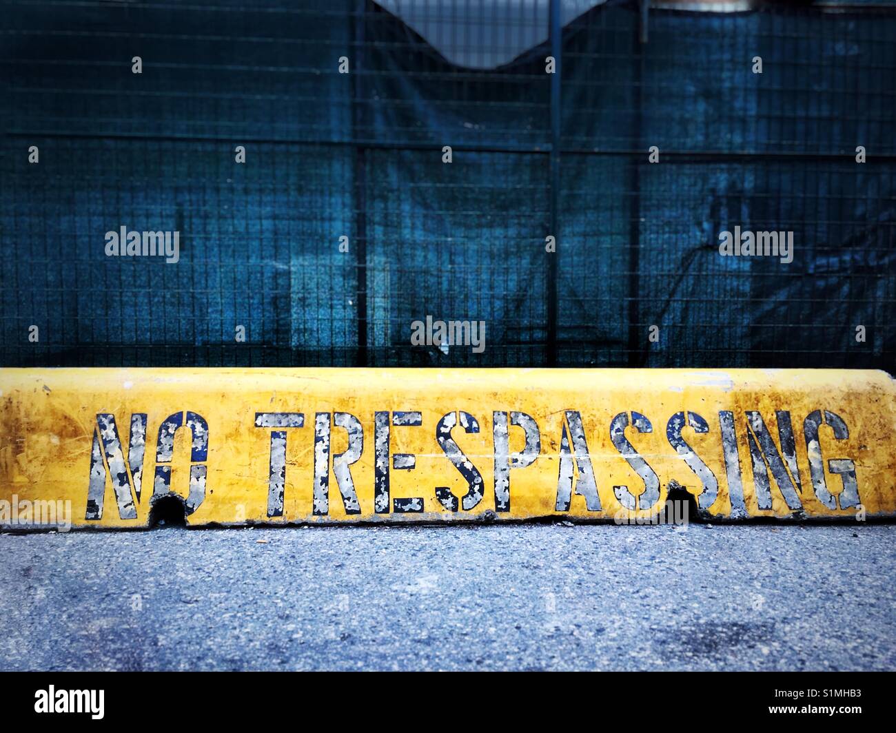 The words 'no trespassing' painted on a yellow barrier at a construction site, North America. - Smartphone Captured Stock Image