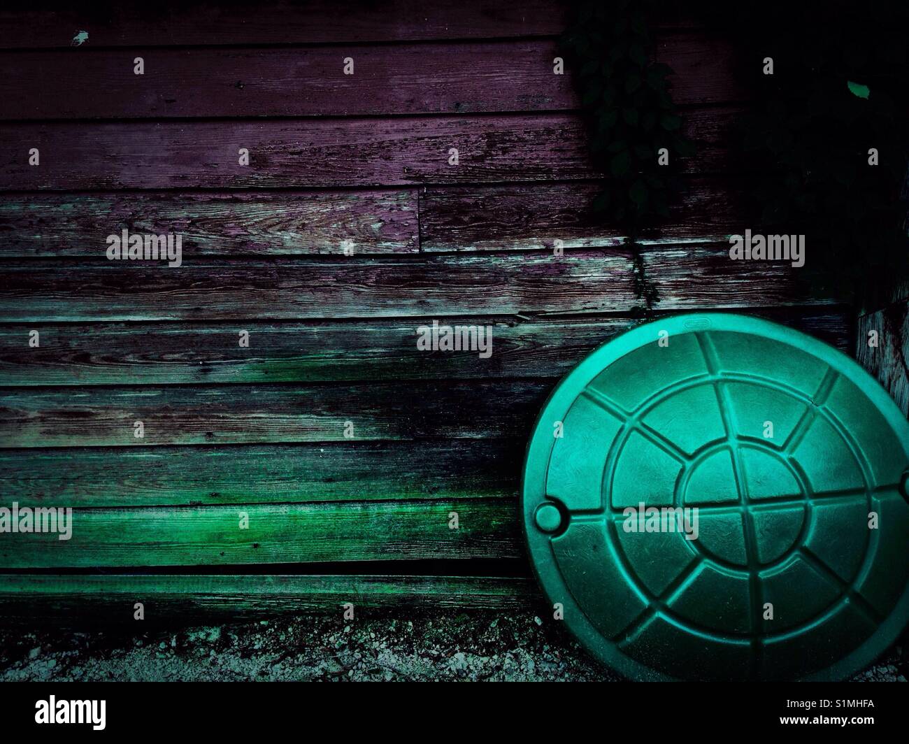 Red shed behind round green sandbox lid with vine - Smartphone Captured Stock Image