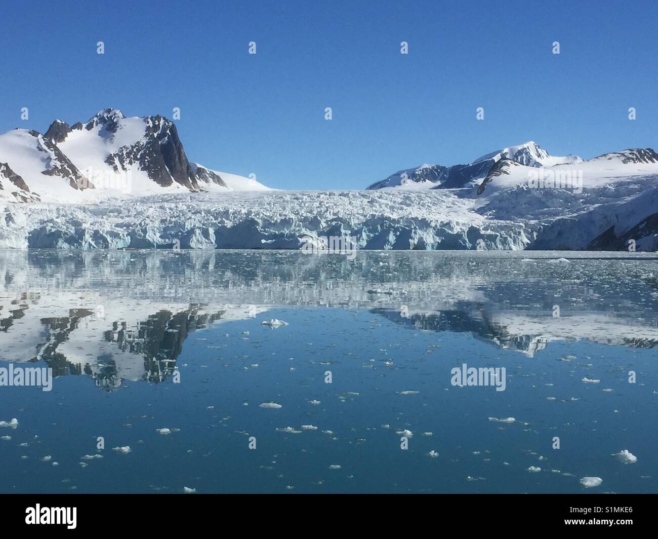 Svalbard - glacier and reflections of the surrounding mountains in the fjord. - Smartphone Captured Stock Image