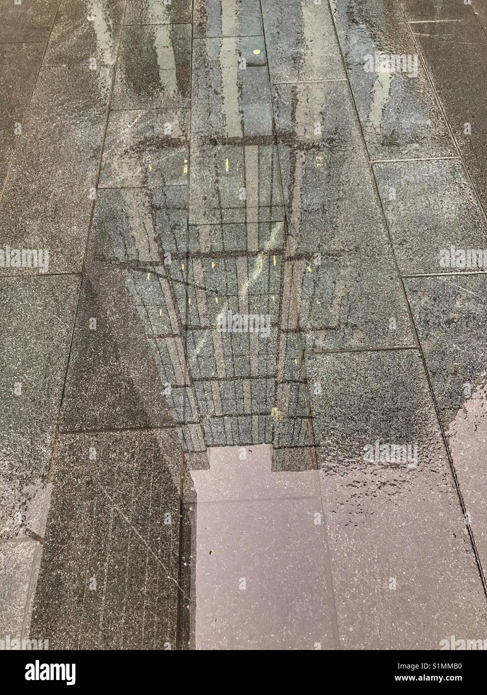 Wet pavement after the rain reflecting modern office buildings - Smartphone Captured Stock Image