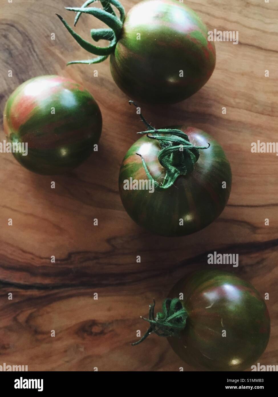 Heirloom cherry tomatoes on wooden cutting board. - Smartphone Captured Stock Image