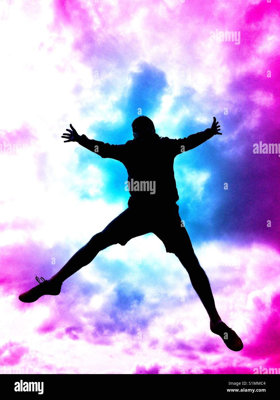 The silhouette of a man jumping high in the air or falling from the sky with a camera stormy sky behind. - Smartphone Captured Stock Image