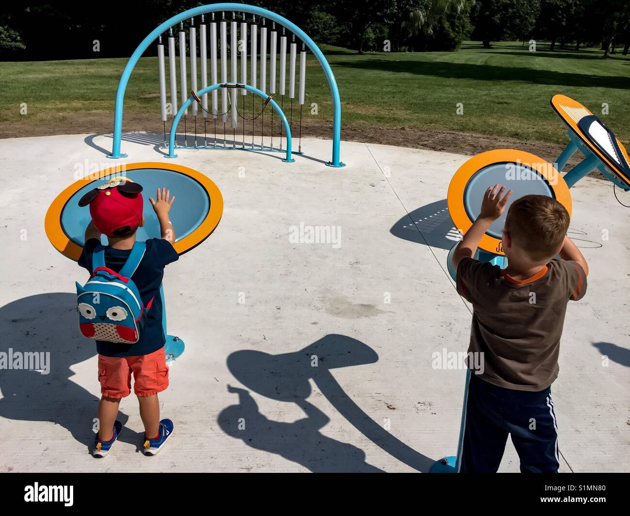 Musical apparatus in a big, public park, with two budding drummers, tomorrow’s stars, drumming in tandem, Ontario, Canada. Open air. Fun. Play. Outing - Smartphone Captured Stock Image