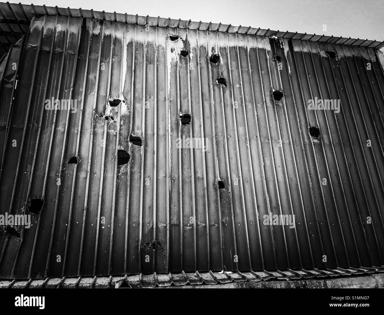 Holes in the side of a warehouse in Aida Camp, Bethlehem, caused by Israeli artillery fire during the second intifada in 2002. Stock Photo