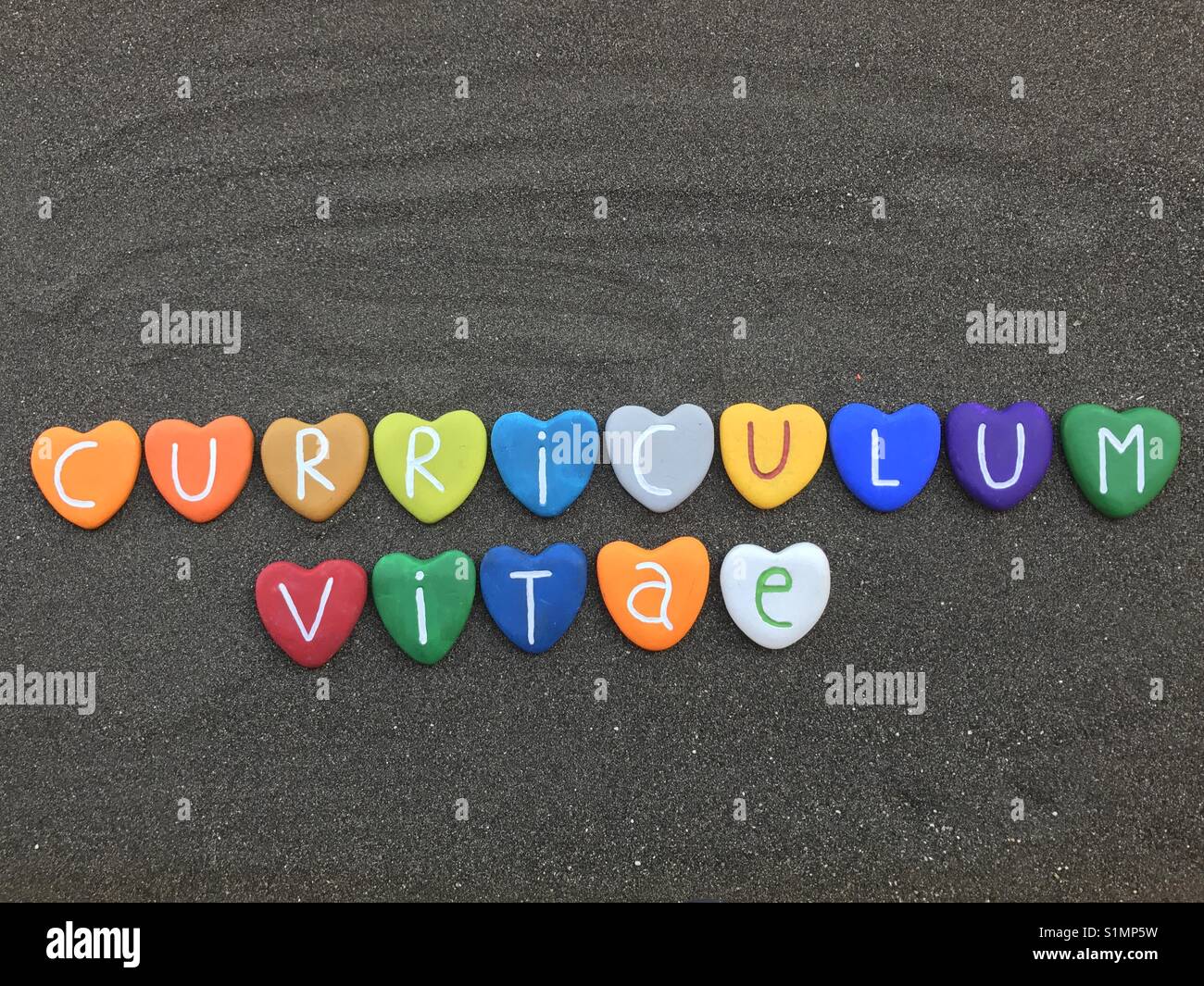 Curriculum Vitae with colored heart stones over black volcanic sand - Smartphone Captured Stock Image