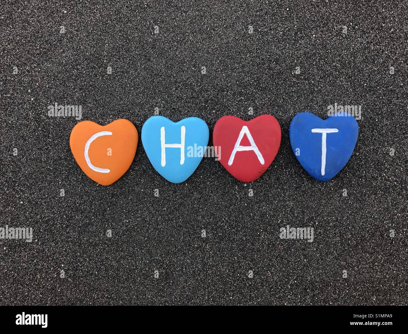 Chat word with colored heart stones over black volcanic sand Stock Photo