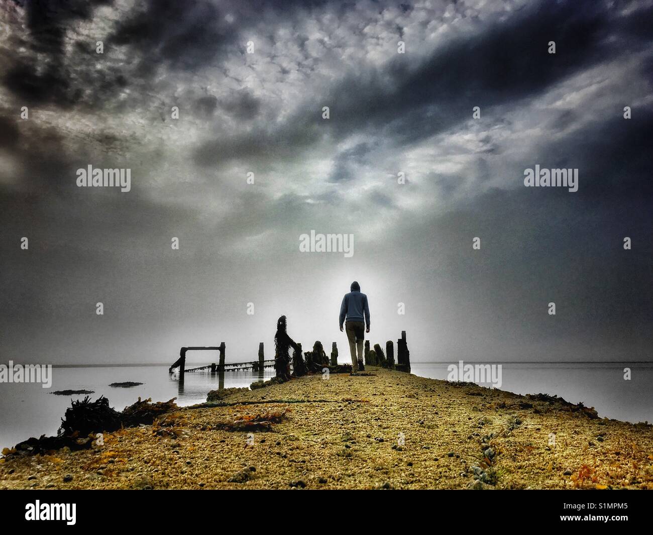 Solitary figure walking down a derelict jetty on a misty morning - Smartphone Captured Stock Image