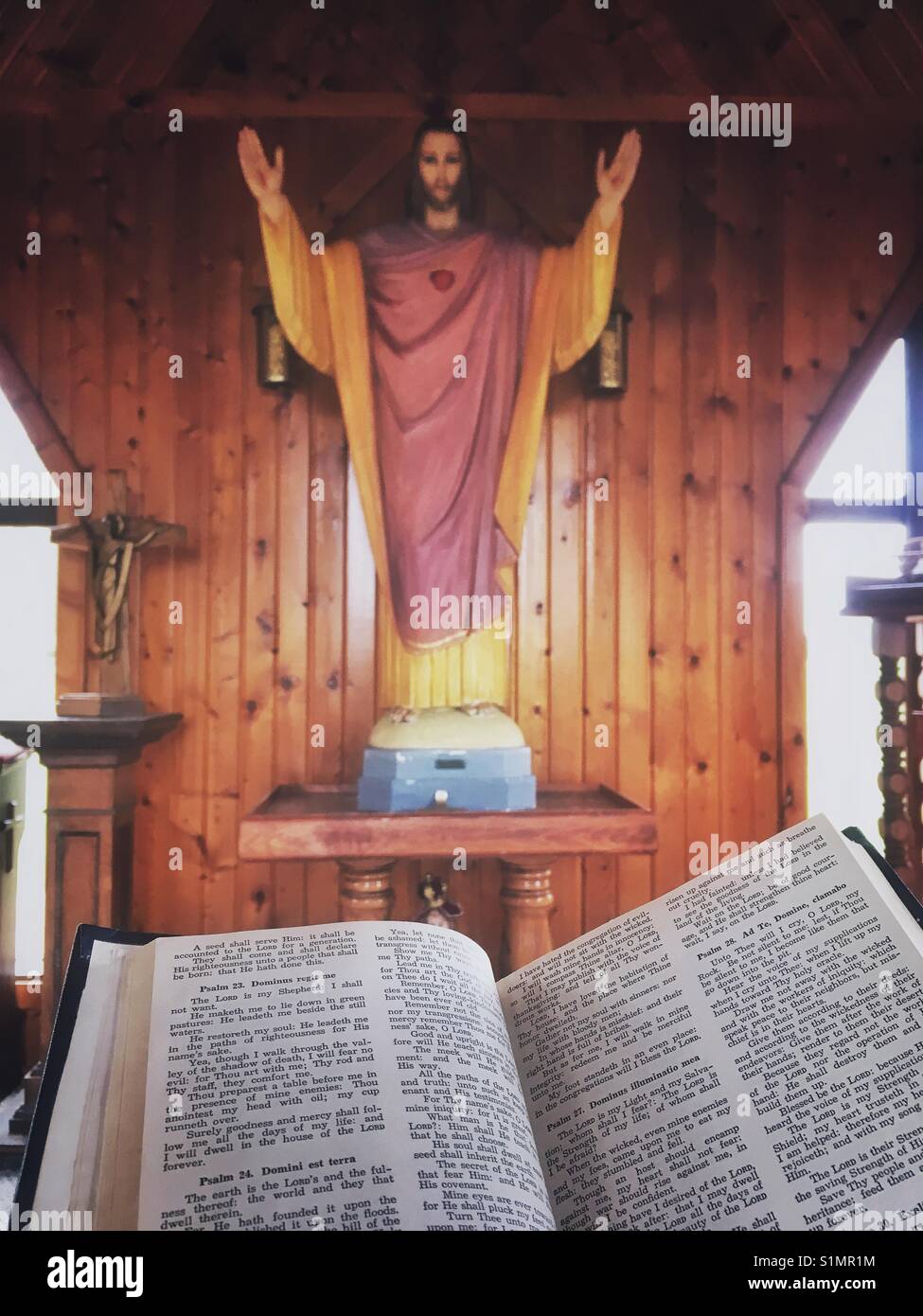 Open bible and a wooden statue of Jesus - Smartphone Captured Stock Image