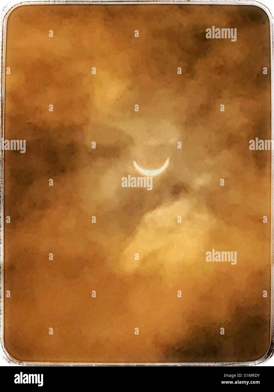 Solar eclipse viewed through hazy clouds in sepia tones, Jacksonville Florida, August 21, 2017 - Smartphone Captured Stock Image