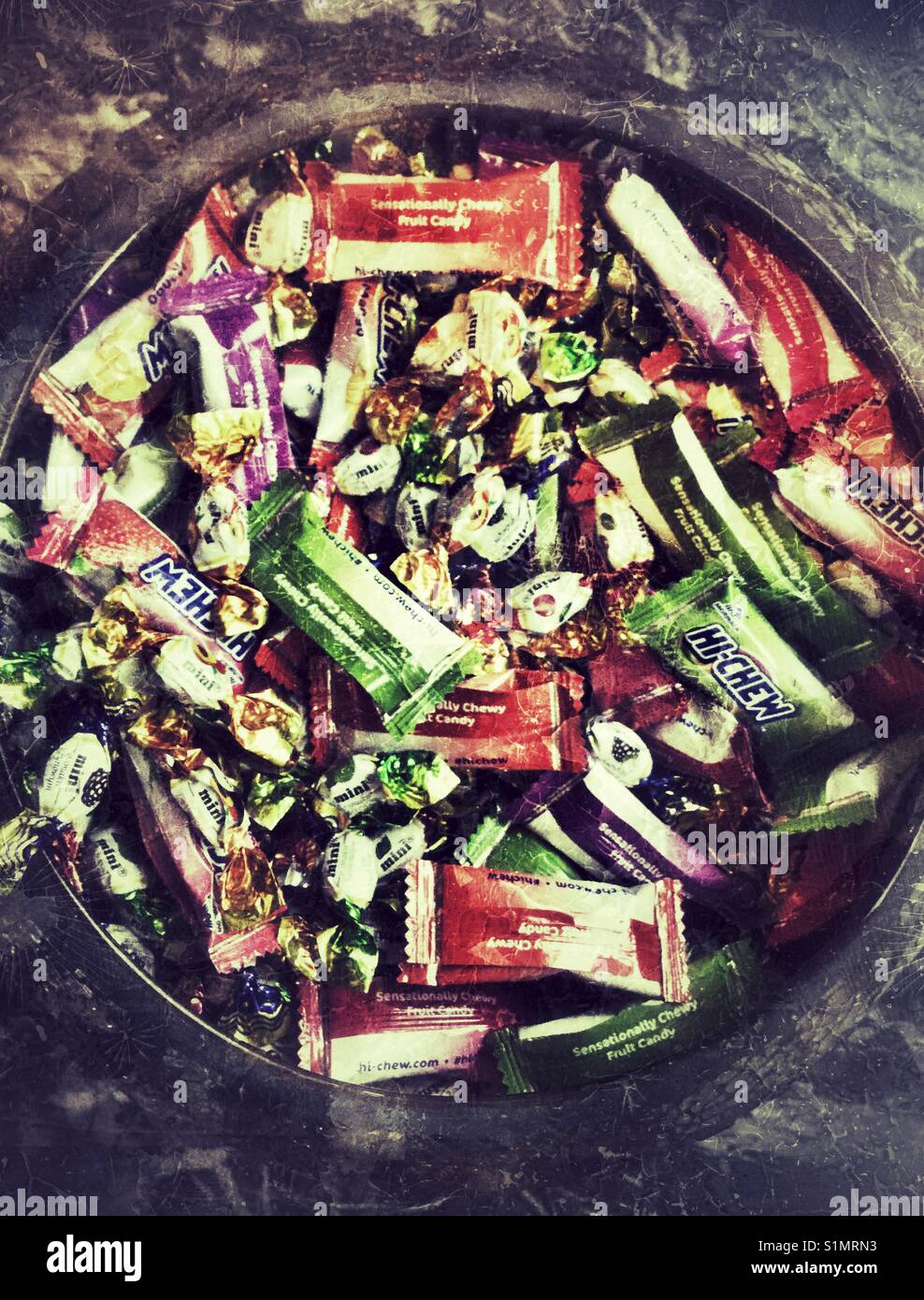 Bowl filled with small wrapped candies. - Smartphone Captured Stock Image