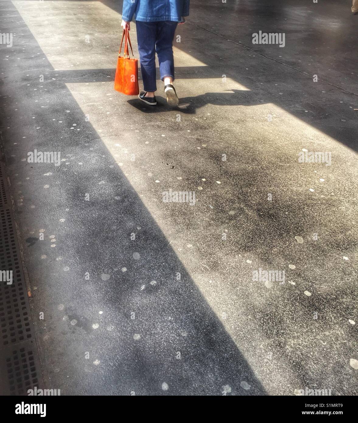 Woman walking with a orange bag - Smartphone Captured Stock Image