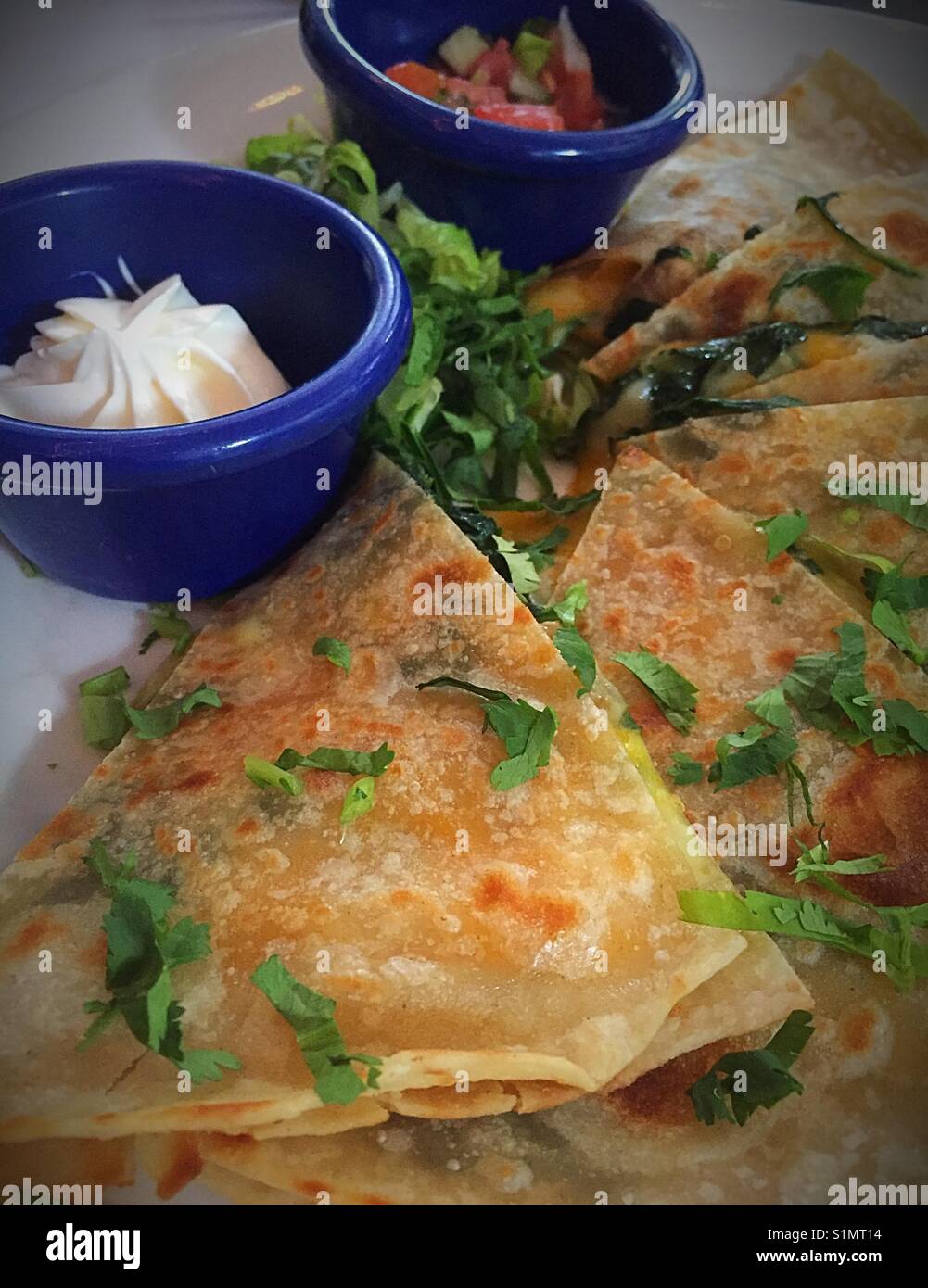 Quesadilla meal at a Mexican restaurant with condiment bowls USA Stock Photo