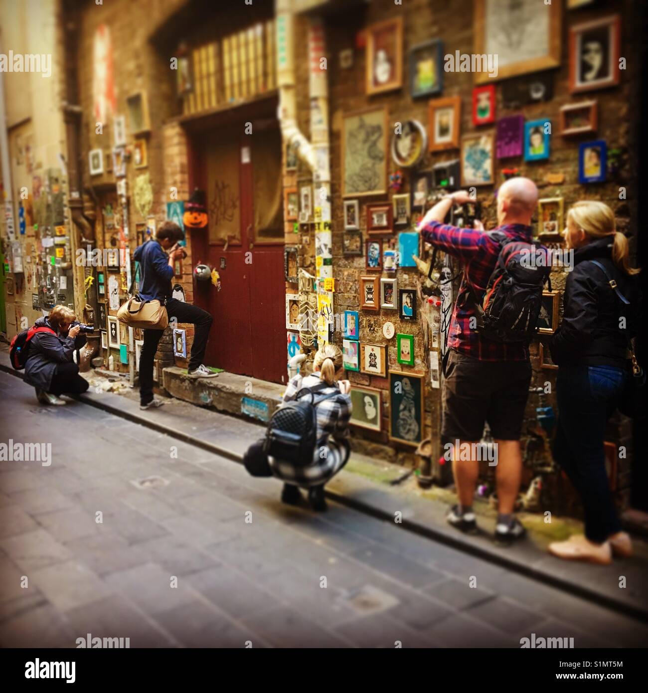 People taking photos in laneway with street art in Melbourne - Smartphone Captured Stock Image