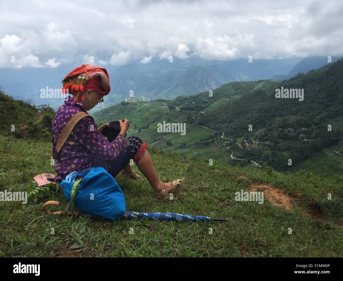 A lady from the Red Dao minority tribe in Northern Vietnam sits doing her embroidery on a mountain top Stock Photo