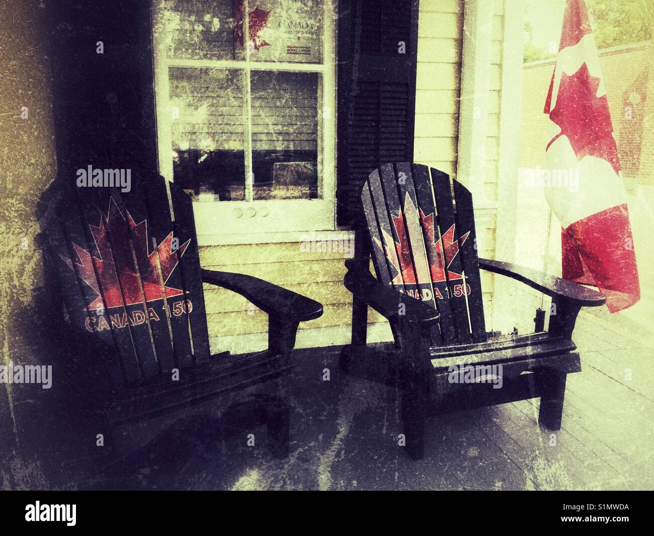 Two black Muskoka chairs with Canadian maple leaf painted on the back rest. Stock Photo