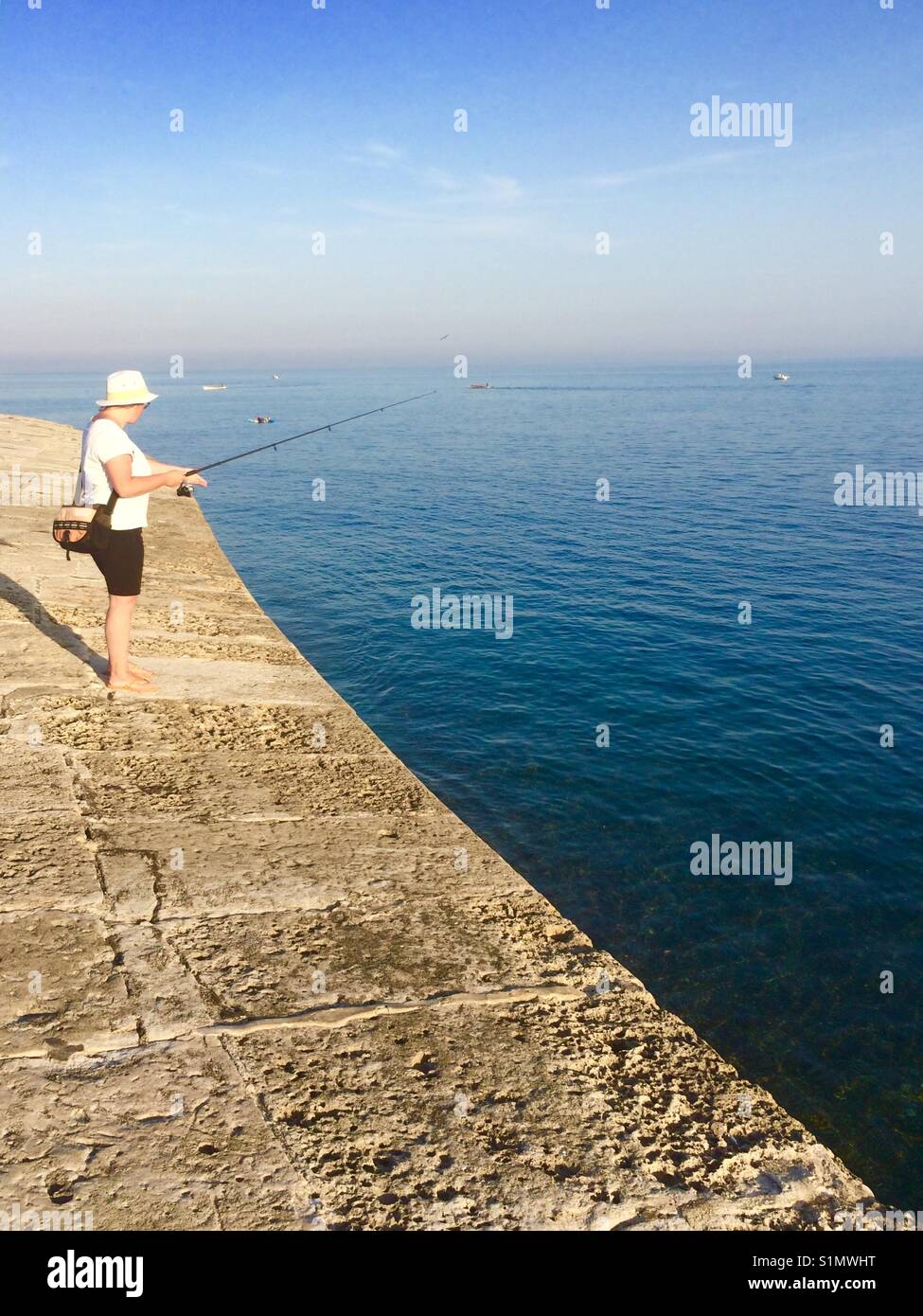 Woman fishing off the cobb Lyme Regis Dorset uk. - Smartphone Captured Stock Image