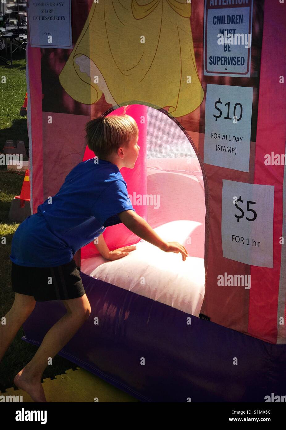 A boy jumps into an inflatable bouncer at a fair. Stock Photo