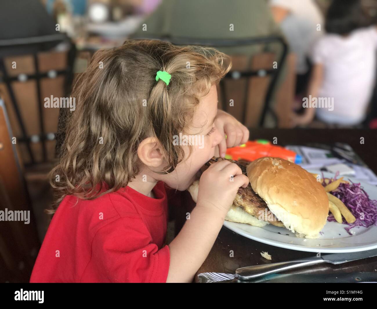 Little girl eating a burger Stock Photo