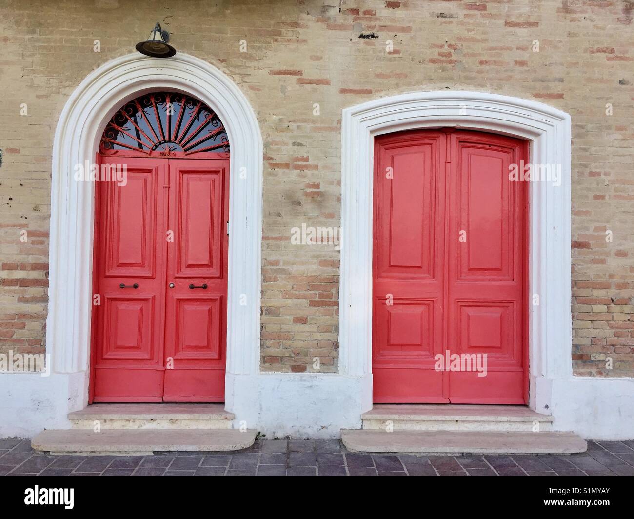 Vintage red painted doors on a bricked house - Smartphone Captured Stock Image