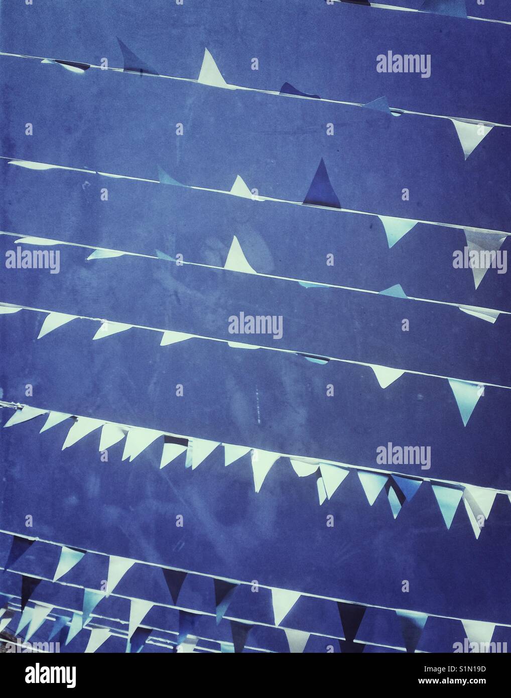 Rows of blue and white bunting and flags hanging over a street under a ...