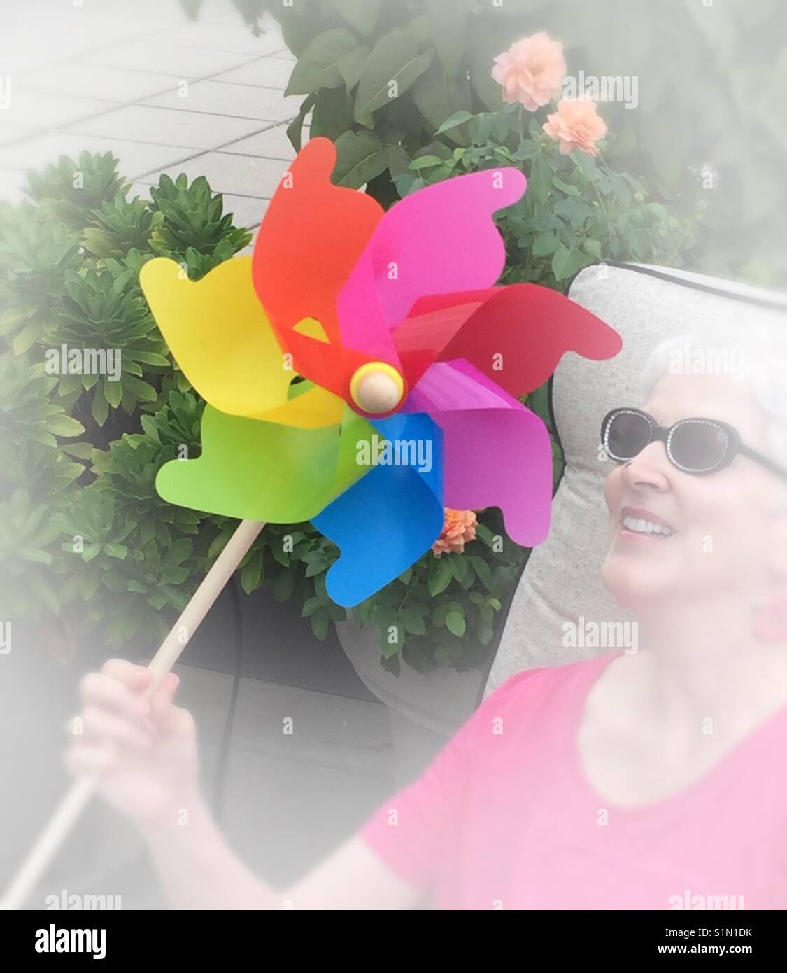 Fun loving seniors woman playing with toy pinwheel, USA - Smartphone Captured Stock Image