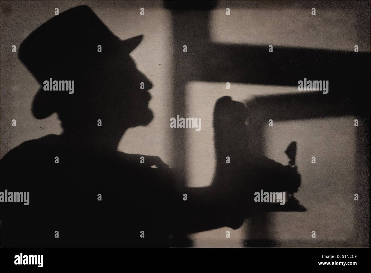 Silhouette of a man wearing a top hat holding a vintage camera - Smartphone Captured Stock Image