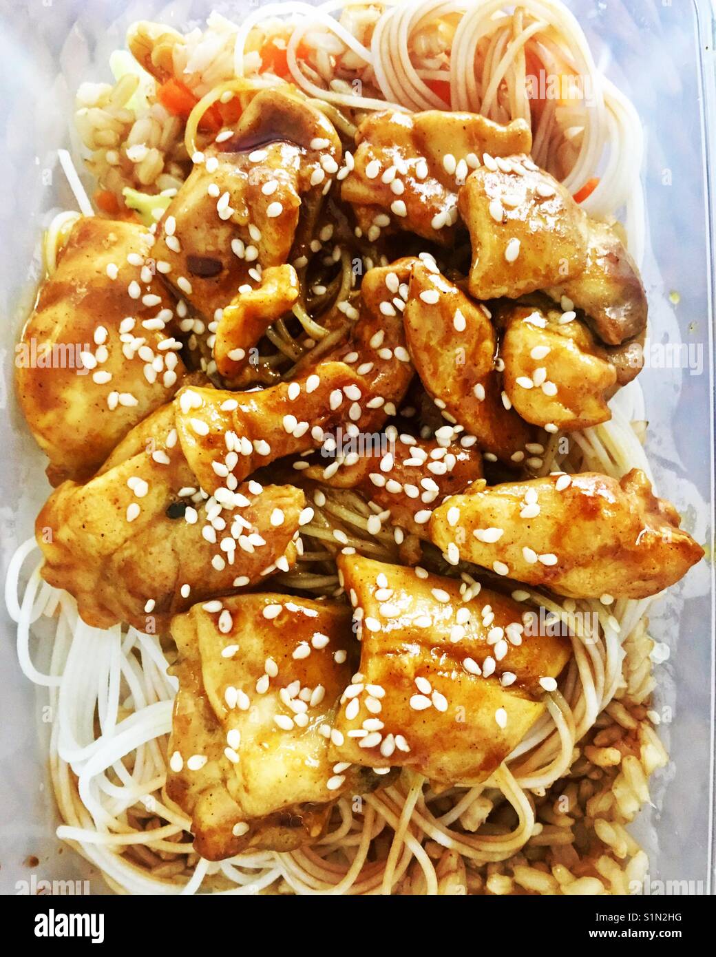 Chicken Teriyaki over noodles and rice garnished with sesame seeds. - Smartphone Captured Stock Image