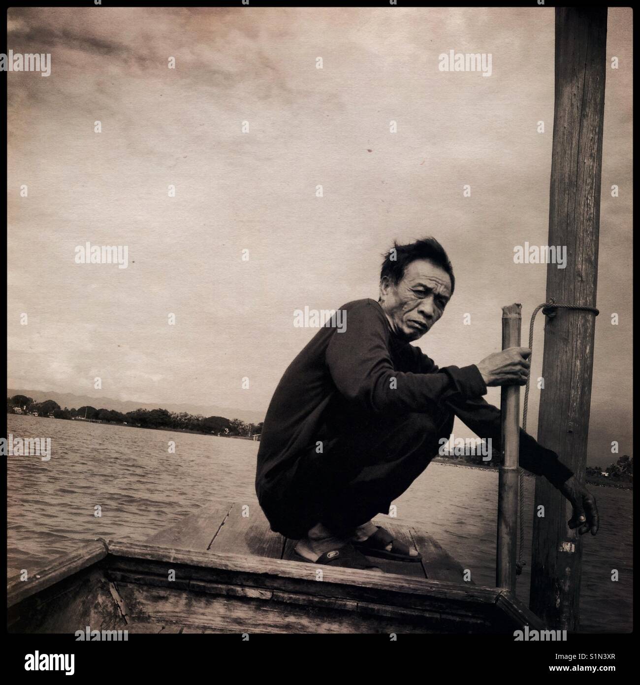 A boatman,who operates the boat between mainland and historical remains of Wat Tilok Aram,a submerged 500-year-old temple, that sits in the middle of Kwan Phayao( Phayao Lake), Phayao, Thailand. Stock Photo