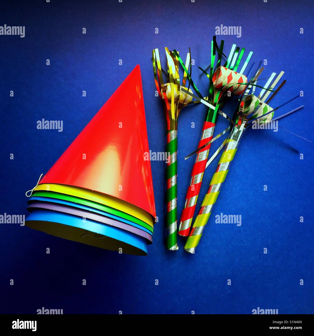 A bright colourful shot of party hats and noise makers on a blue
