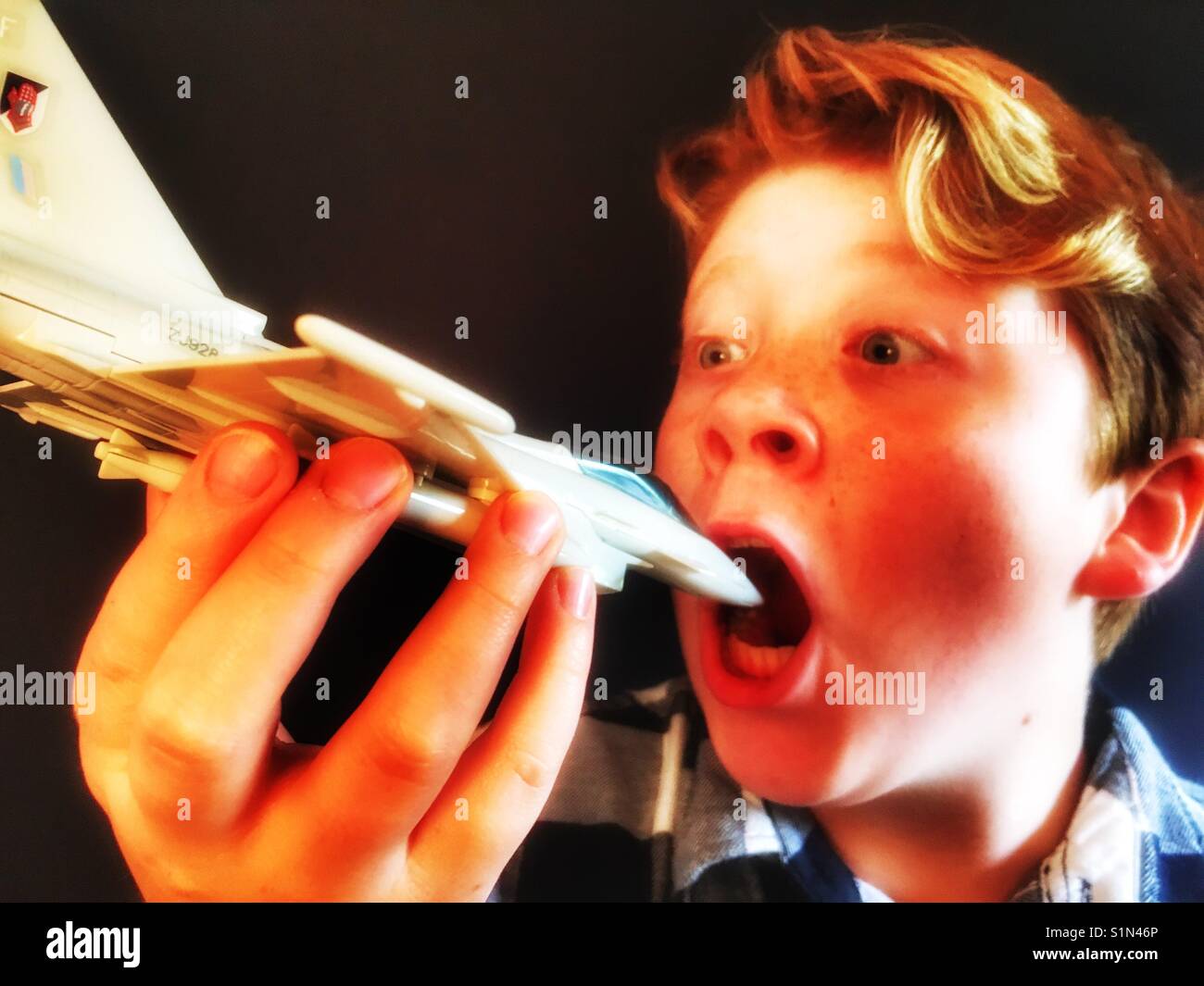 11-year old boy playing with toy fighter jet - Smartphone Captured Stock Image