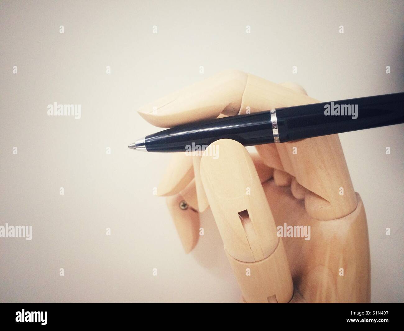 Wood mannequin hand holding a black pen Stock Photo