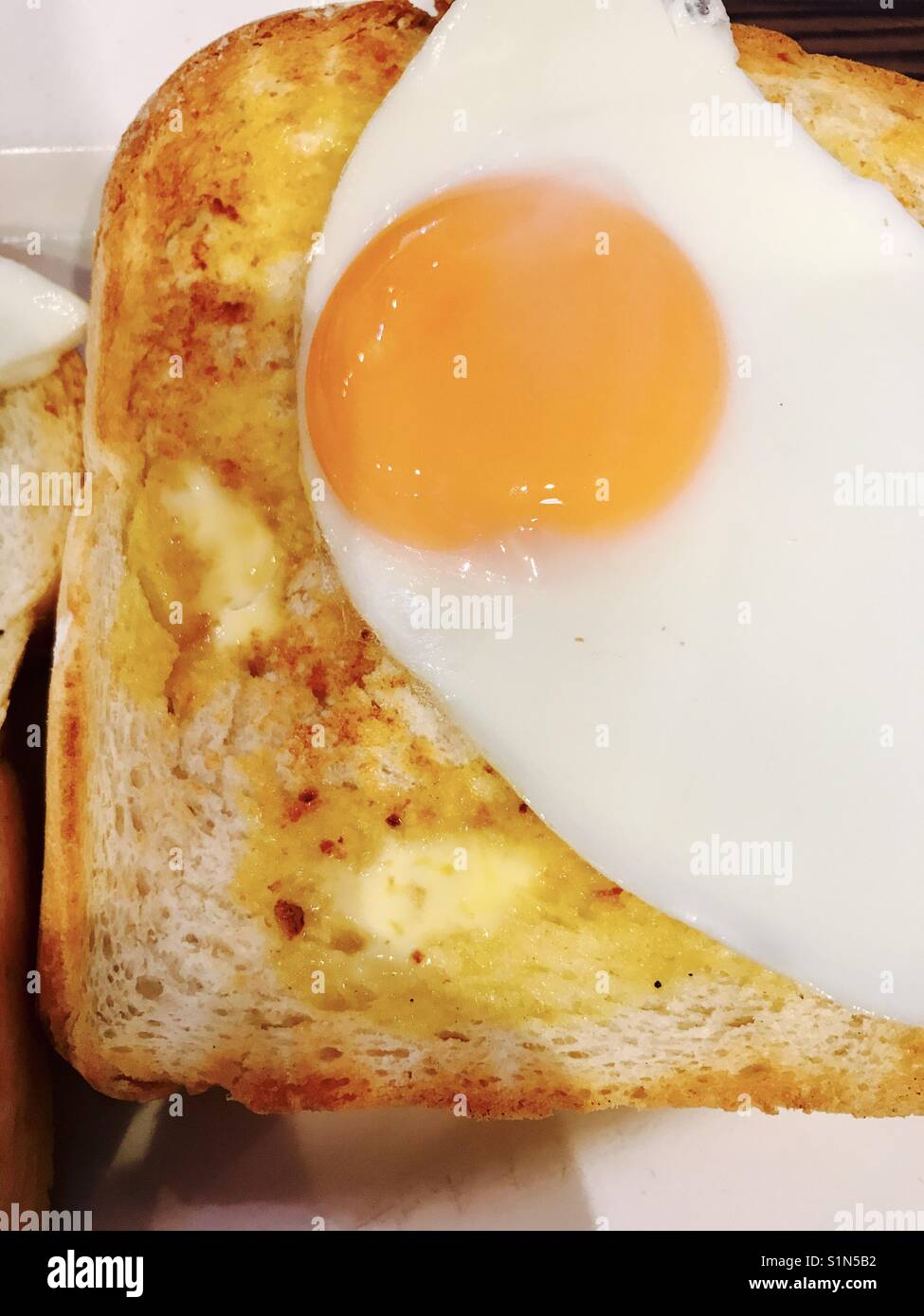 Fried egg on hot white buttered toast Stock Photo Alamy
