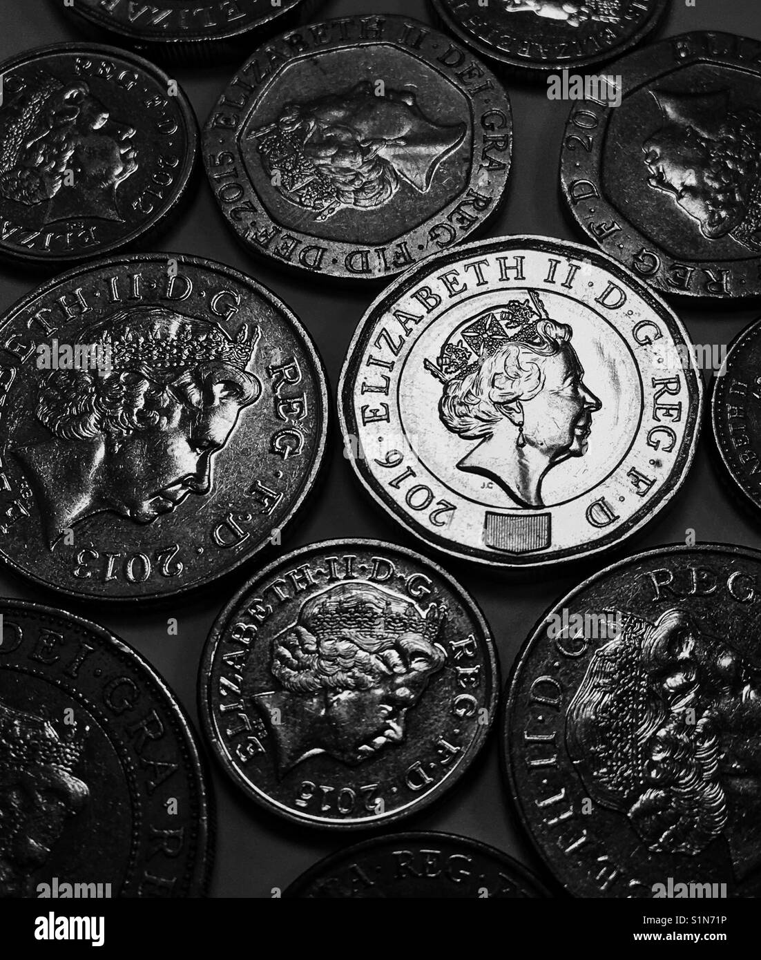 New Pound Coin glows amidst older coins. Stock Photo