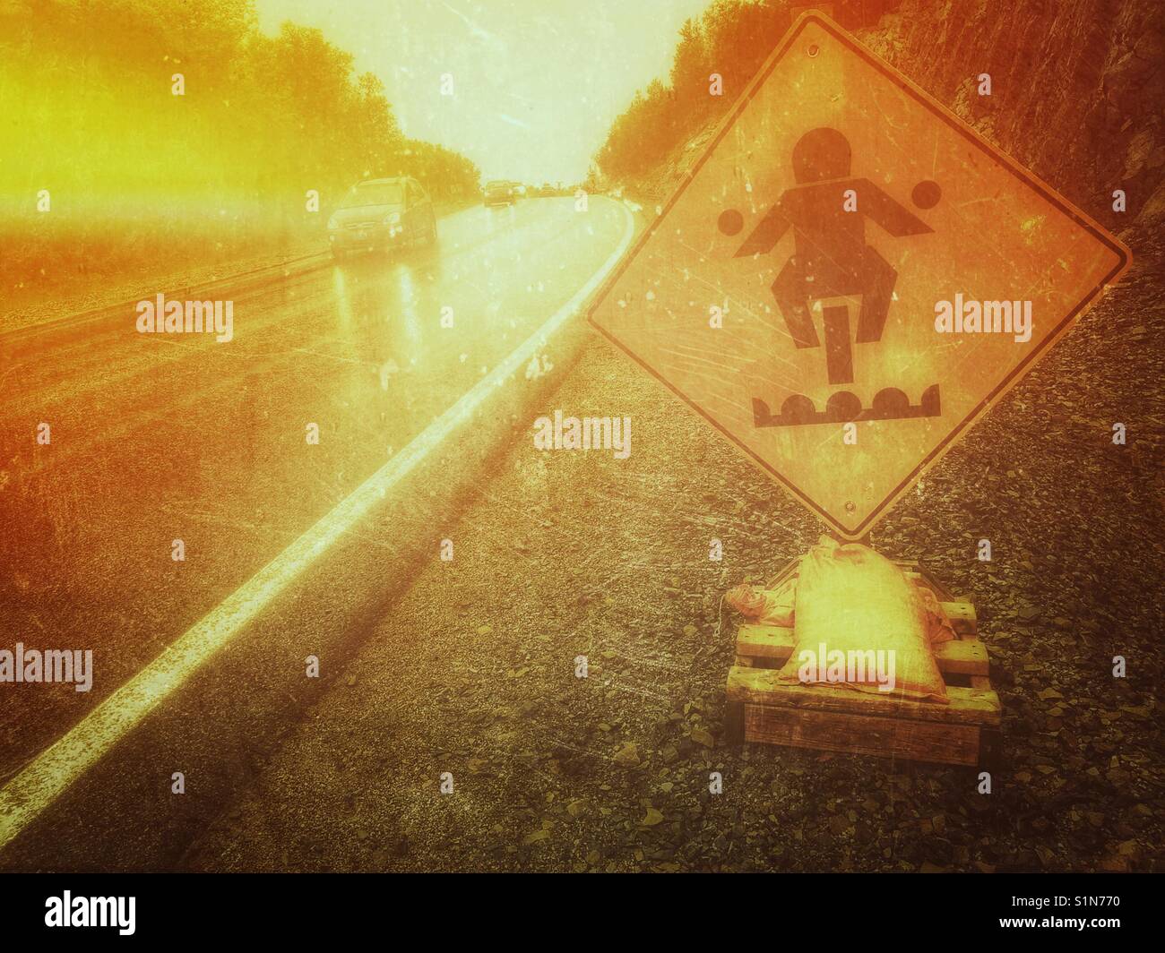 Bumpy road ahead warning sign for motorcyclists next to wet highway, Canada - Smartphone Captured Stock Image