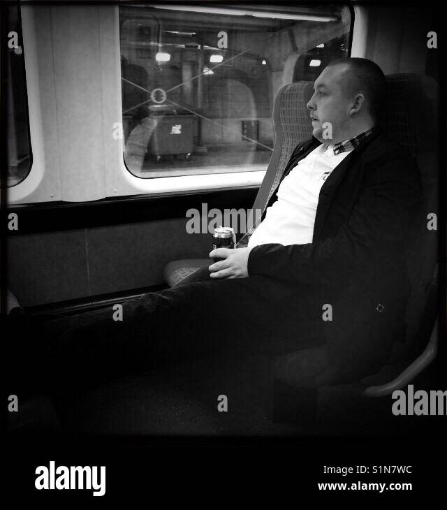 Man sitting on train drinking beer London - Smartphone Captured Stock Image