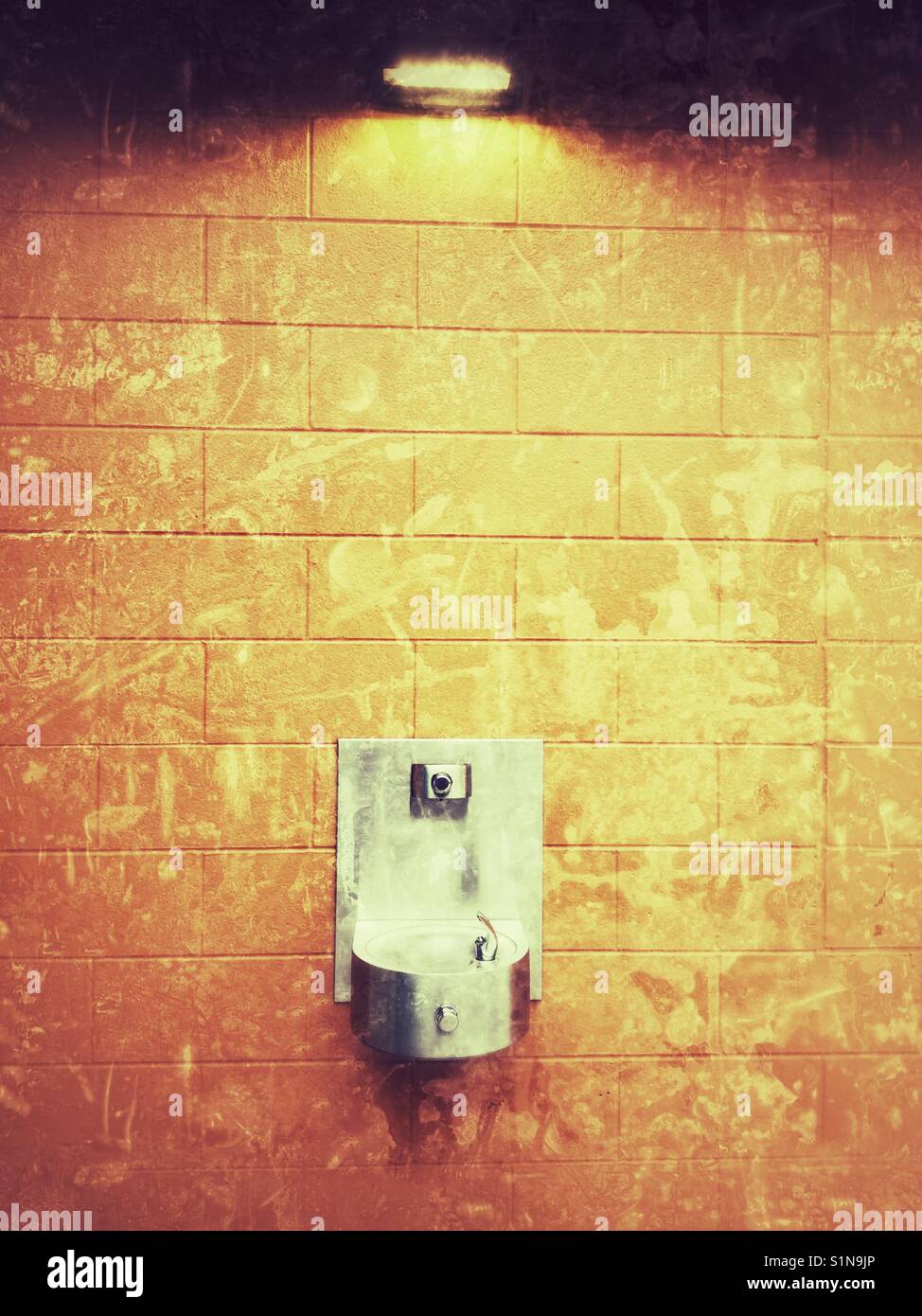 Drinking fountain on a bright orange wall. Stock Photo