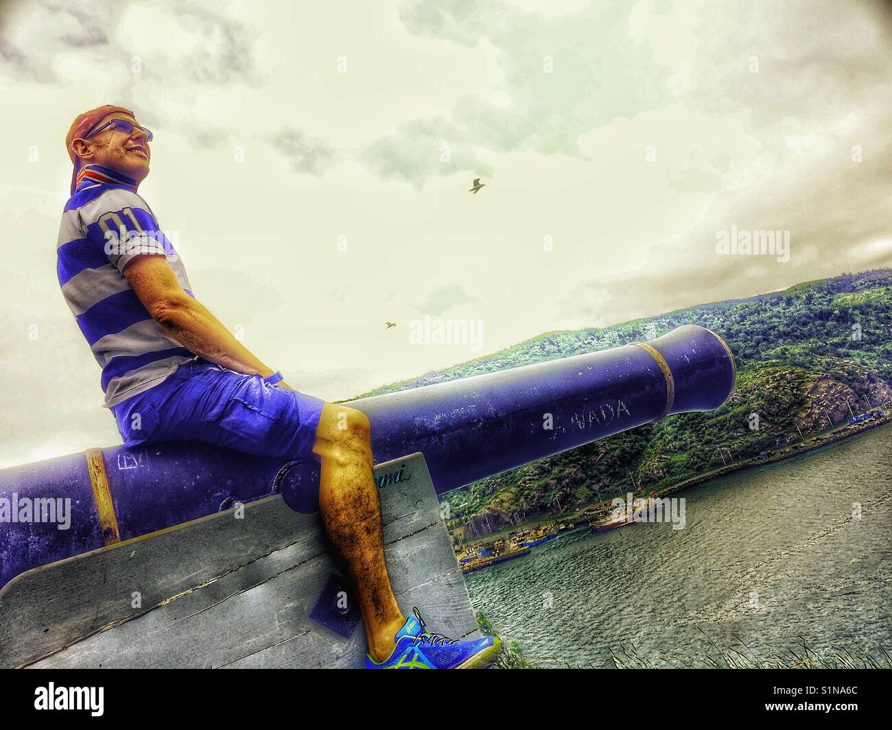 Middle aged Scandinavian man posing on cannon - Smartphone Captured Stock Image