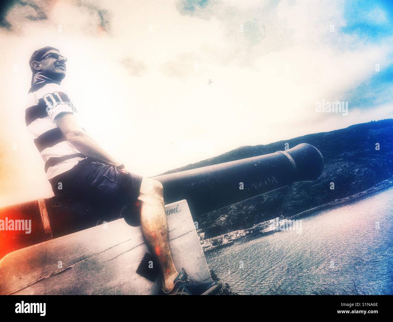 Middle aged Scandinavian man posing on cannon - Smartphone Captured Stock Image